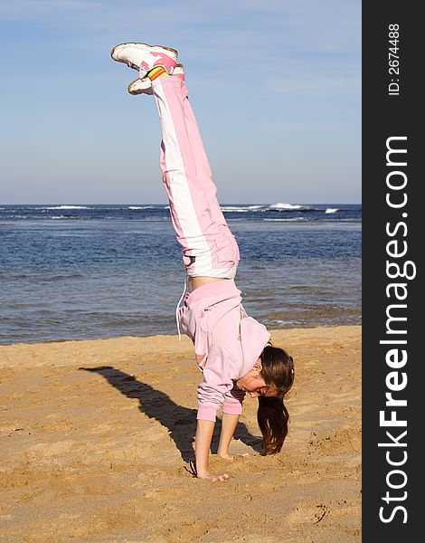 Girl on beach doing a handstand