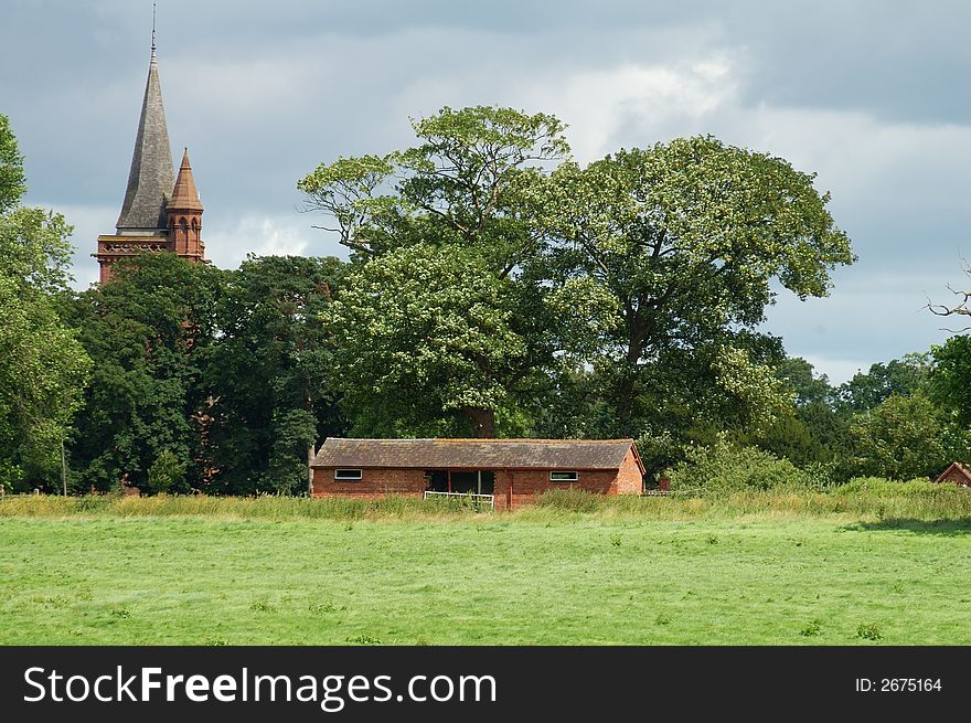 Rundown old building being used as a cowshed in the countryside with a church spire in the background. Rundown old building being used as a cowshed in the countryside with a church spire in the background.