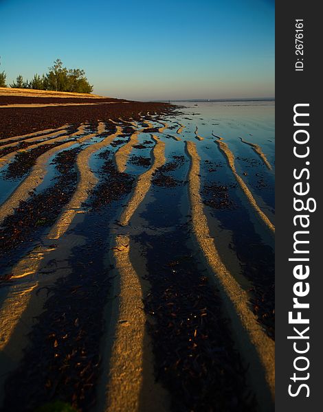 Another beach scene with ripples in the sand caused by the waves.