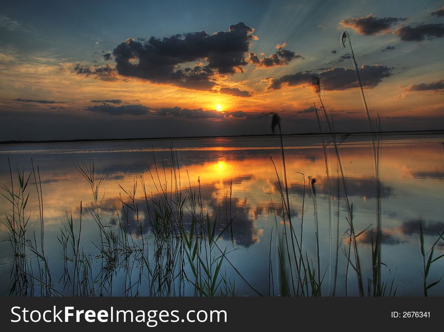 Sunset over a lake with clouds reflection in a water. Sunset over a lake with clouds reflection in a water