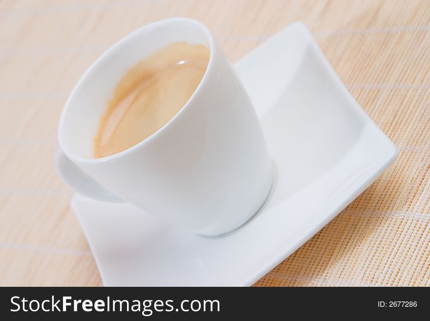 A cup of espresso on a white square saucer. A cup of espresso on a white square saucer