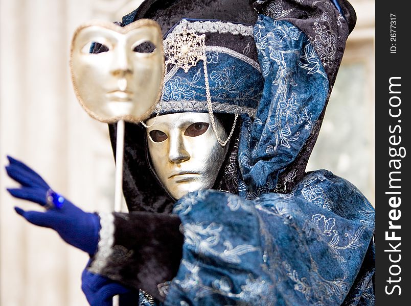 A man in a golden mask and blue costume at the Venice Carnival