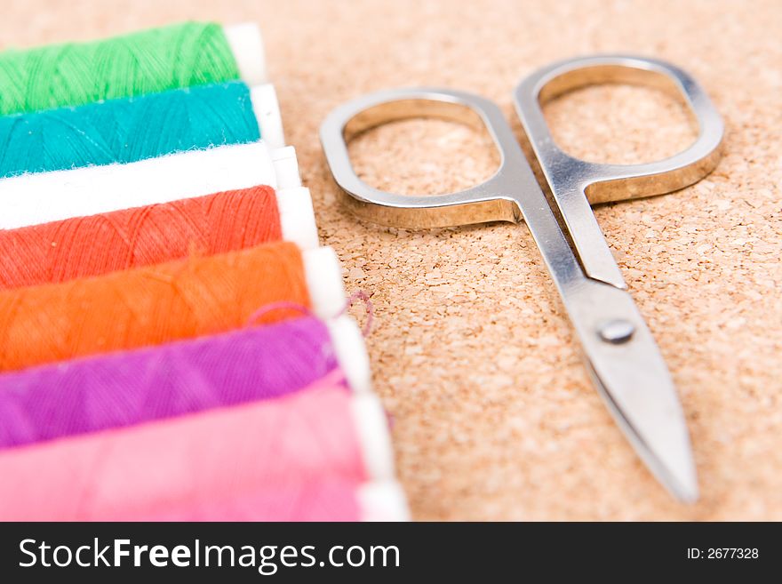 Rolls of colorful cotton with selective  focus on the scissors