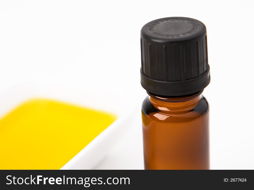 A brown bottle with a bath of oil in the background. A brown bottle with a bath of oil in the background