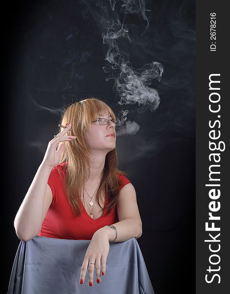 Girl smoking a cigarette on a dark background. Girl smoking a cigarette on a dark background