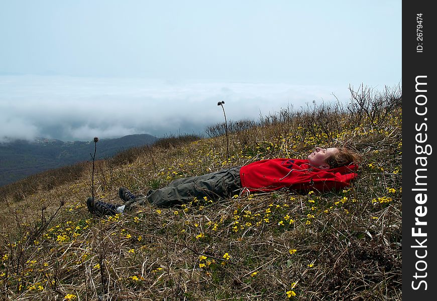 Girl куыештп  on the mountain flower meadow against cloud landscape. Girl куыештп  on the mountain flower meadow against cloud landscape