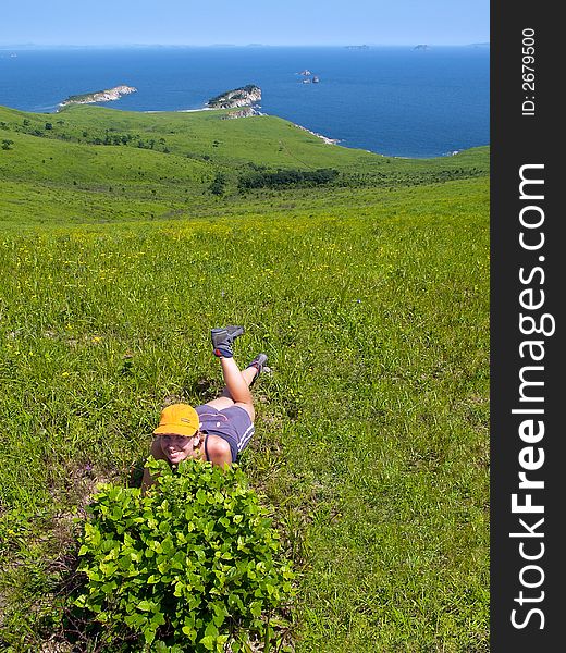 Happy girl  lying on the meadow against fine sea coast landscape. Happy girl  lying on the meadow against fine sea coast landscape