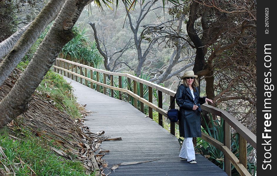 A woman walking and taking photographs on walking track of nature reserve at Point Lookout, Stradbroke Island, Queensland, Australia. A woman walking and taking photographs on walking track of nature reserve at Point Lookout, Stradbroke Island, Queensland, Australia.