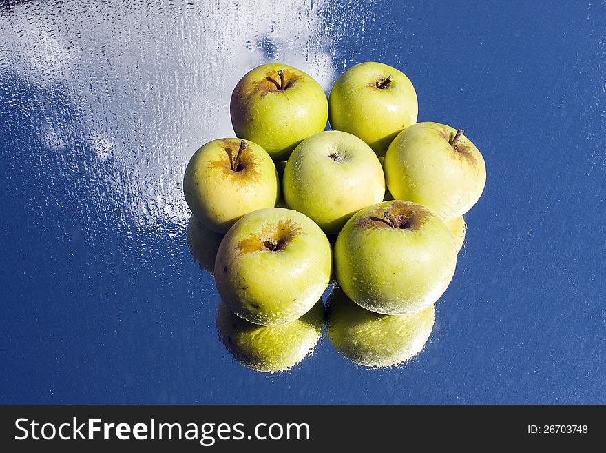 Six yellow apples in flower formation on wet, reflective glass. Six yellow apples in flower formation on wet, reflective glass.