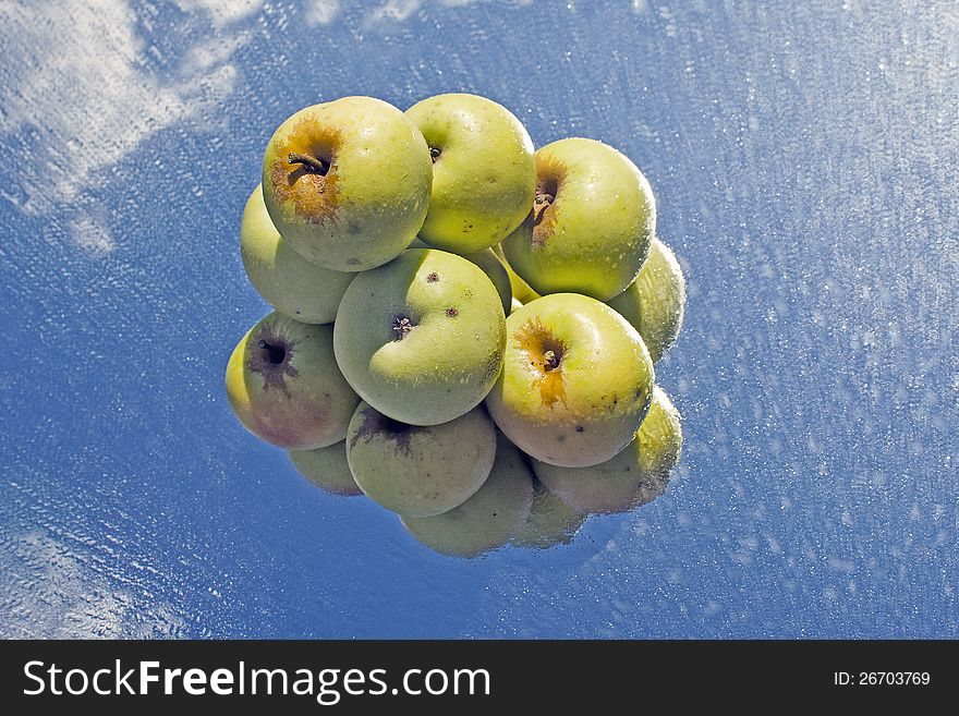 Yellow apples stocked in pyramid on wet, reflective glass. Yellow apples stocked in pyramid on wet, reflective glass.