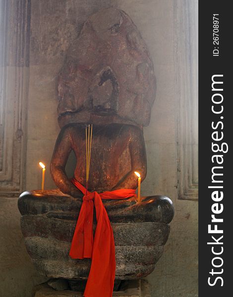 Candles burning and cloth at an old Hindu statue at Angkor Wat temple in Cambodia.