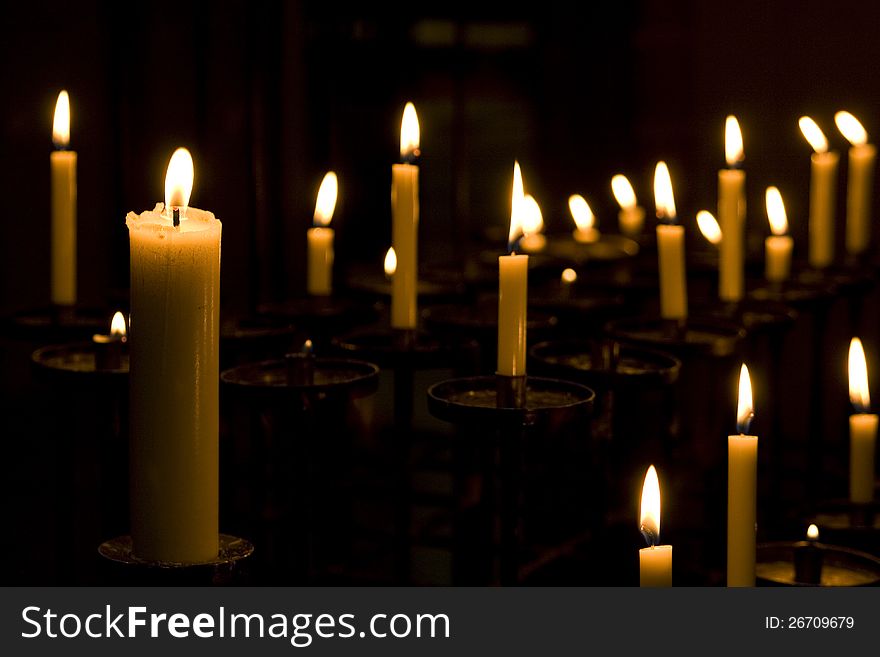 Many candles burning at a dim church. Many candles burning at a dim church.