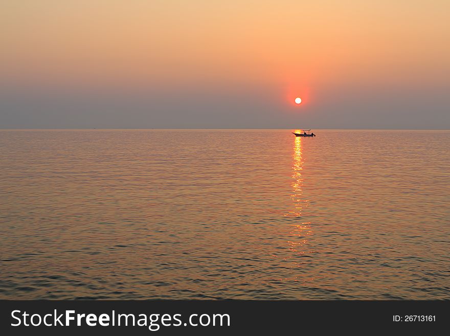 A small fishing boat in the sea at sunset.