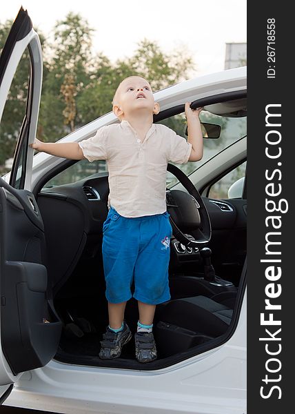 Small boy standing in a car door