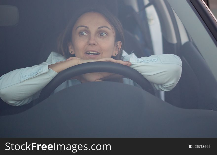 View through the windscreen of a harassed woman waiting in car with her hands and head resting on the steering wheel