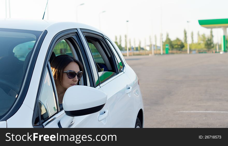 Female driver looking out of her open side window to check for traffic as she leaves a gas station. Female driver looking out of her open side window to check for traffic as she leaves a gas station