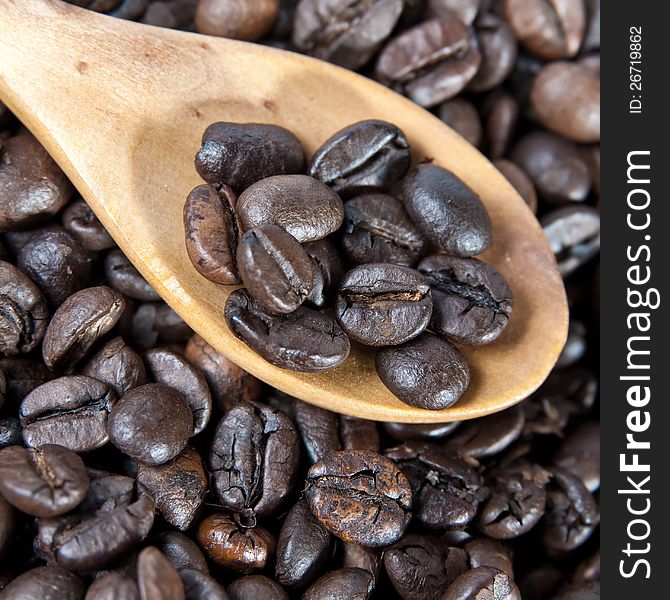 Coffee beans with wooden spoon close-up on a coffee beans background