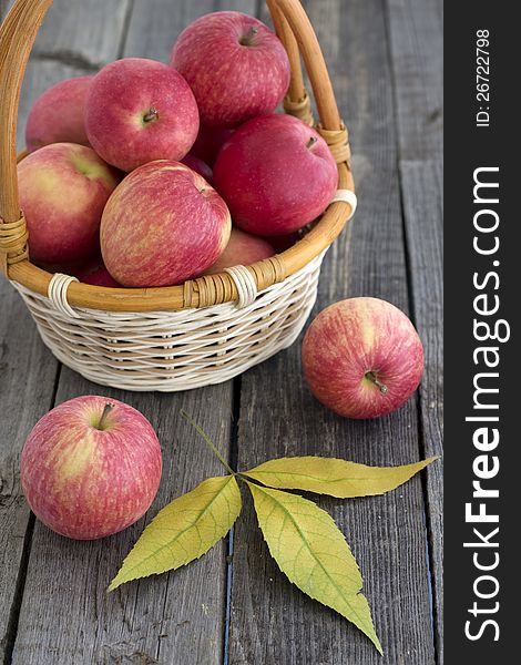 Red apples in a basket and autumnal leaves