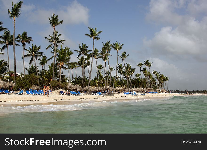 A view of the beach with palm trees, umbrellas and sun beds from the sea in Punta Cana Dominican. A view of the beach with palm trees, umbrellas and sun beds from the sea in Punta Cana Dominican