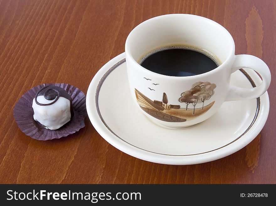 Cup of black coffee and candy on table. Close up.