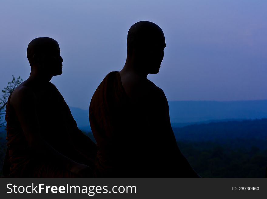 Silhouette of monk meditating at the top of the mountain