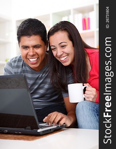 Happy young couple looking at a laptop