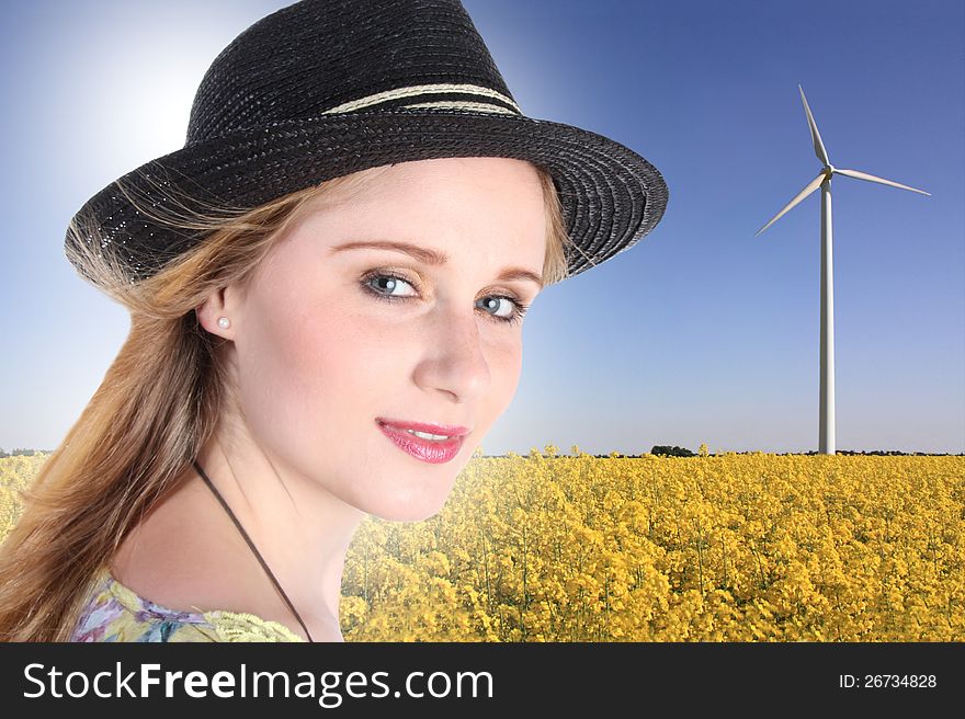 Young woman with windturbine and raps field in background