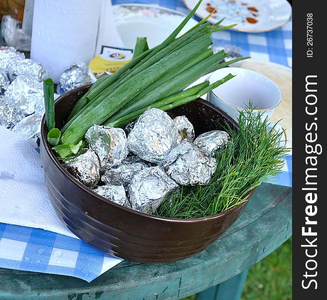 Green onion and potato in a foil in a pot