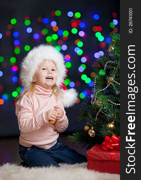 Pretty preschool girl decorating Christmas tree over bright festive background. Pretty preschool girl decorating Christmas tree over bright festive background