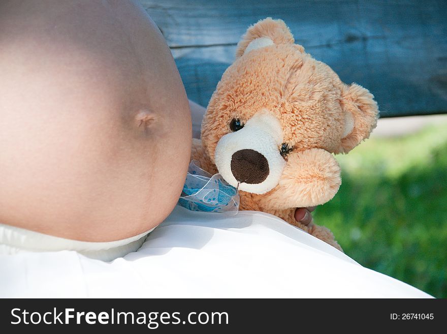 Pregnant woman holding teddy bear next to her belly