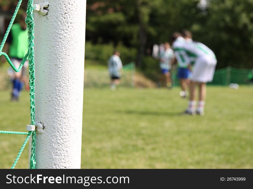 Green football net, green grass and players