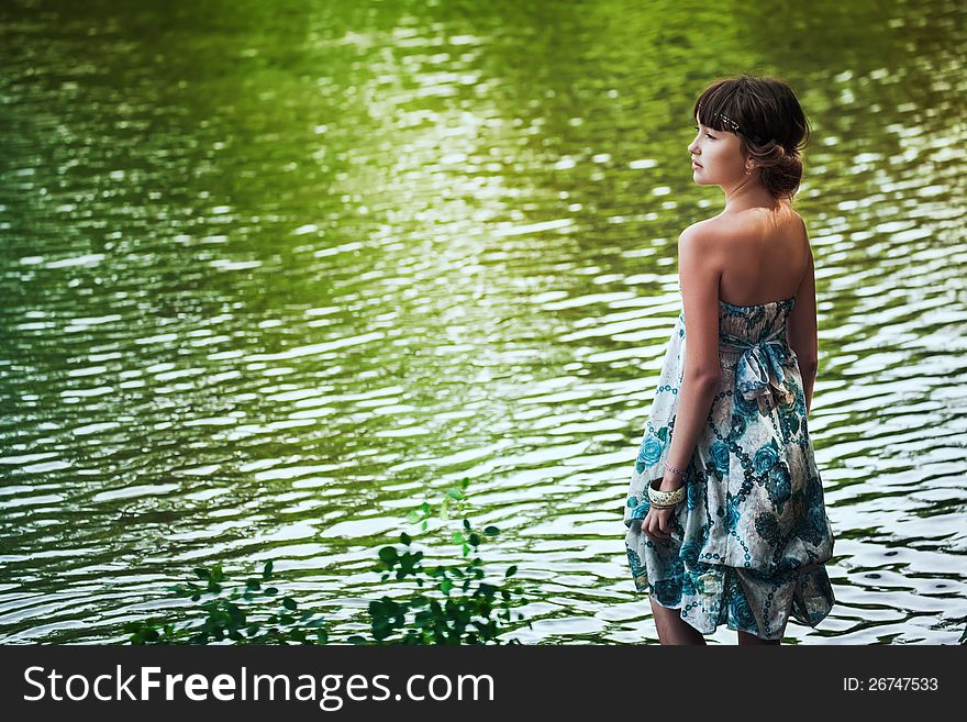 Girl in blue dress stayingby a lake. Girl in blue dress stayingby a lake