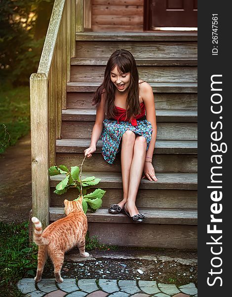 Girl in red dress playing with cat. Girl in red dress playing with cat