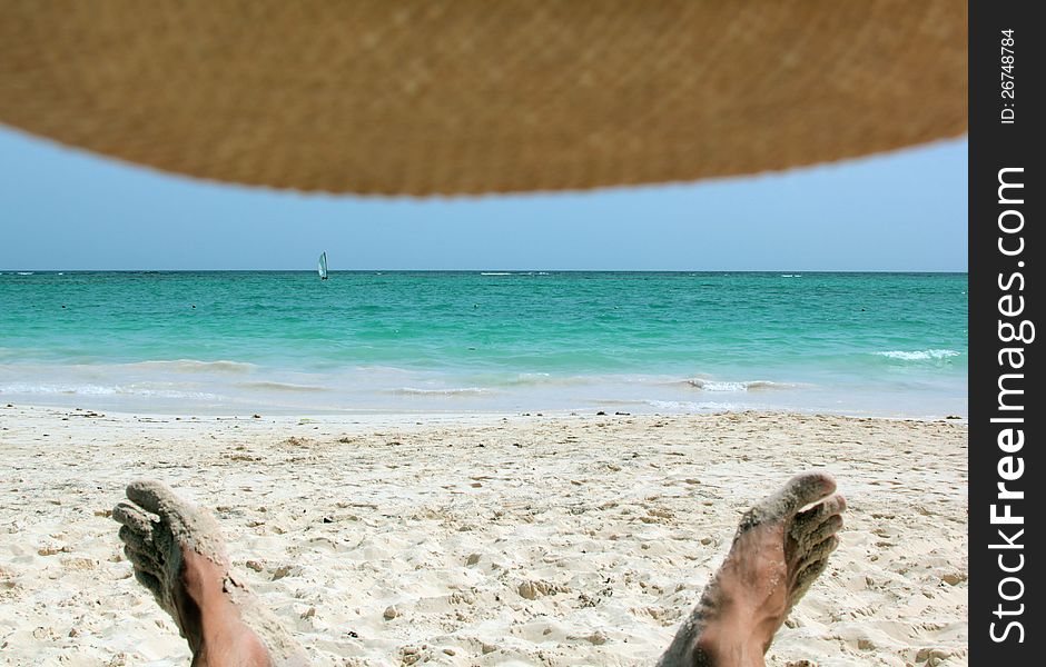 A look at the sea and the beach from under the hat, you can see mens legs, Bavaro, Punta Cana, Dominican Republic, Caribbean. A look at the sea and the beach from under the hat, you can see mens legs, Bavaro, Punta Cana, Dominican Republic, Caribbean