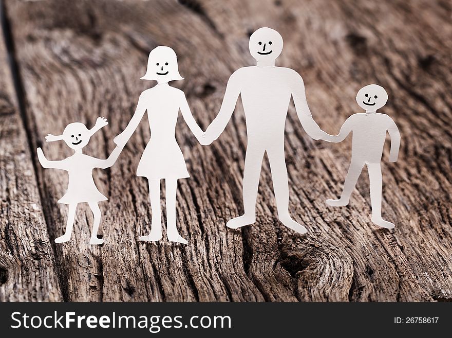 Cardboard figures of the family on a wooden table. The symbol of unity and happiness.