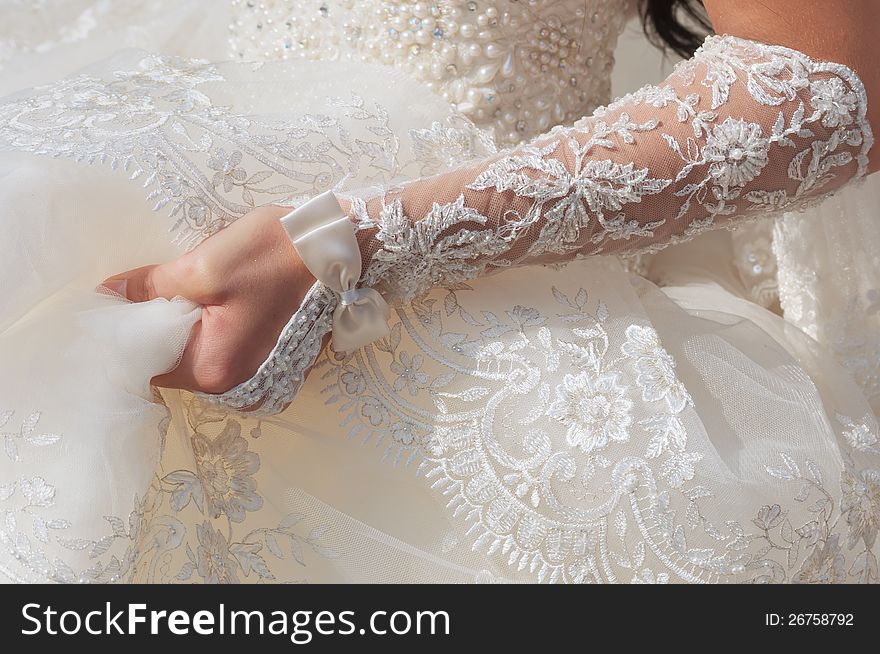 Bride hand on the white dress background with lace decoration. Bride hand on the white dress background with lace decoration