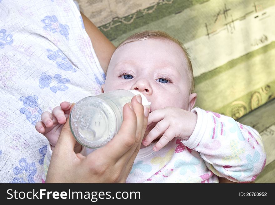 Mom feeding a child a bottle of milk. Mom feeding a child a bottle of milk