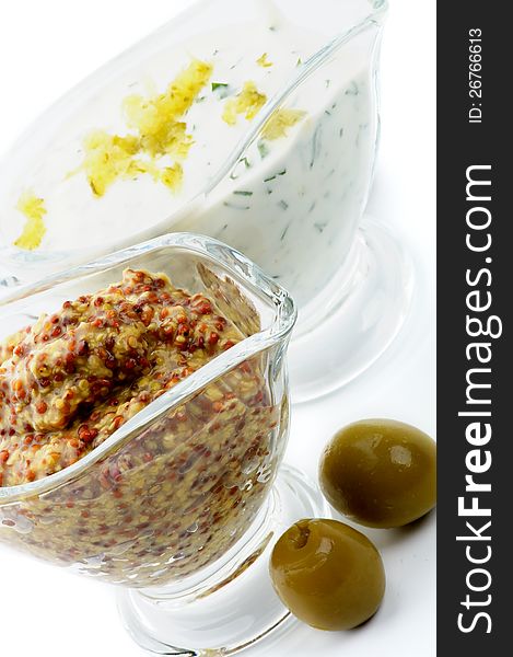 Whole Grain Mustard and Tartar Sauce with two Olives in Glass Gravy Boat on white background