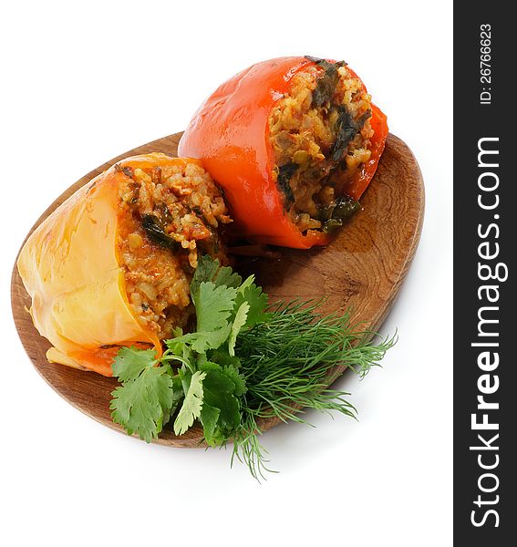 Stuffed Red and Yellow Bell Peppers Filled with Rice, Meat, Onion and Parsley close up on wooden plate