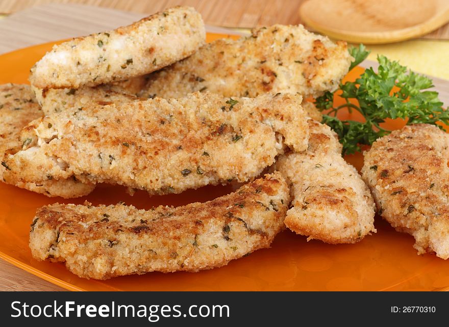 Chicken breast tenderloins on an orange platter