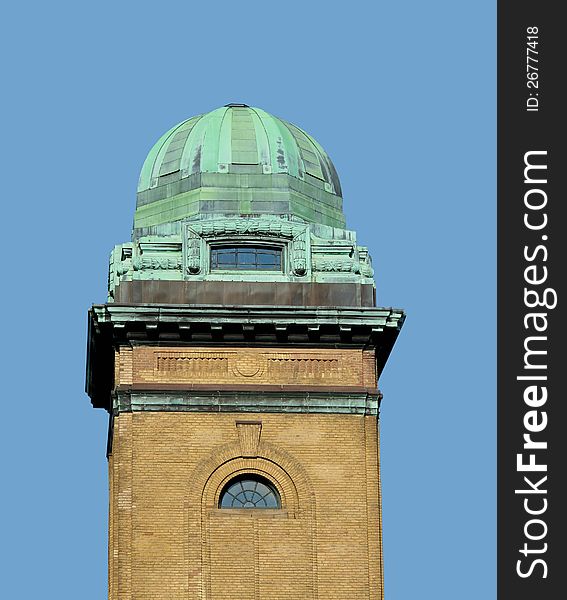 Green weathered copper dome or cupola, with a window, on top of an old brick tower. Isolated against a blue sky. Green weathered copper dome or cupola, with a window, on top of an old brick tower. Isolated against a blue sky.