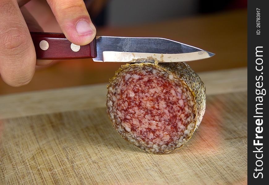 Cutting salami on a wooden board