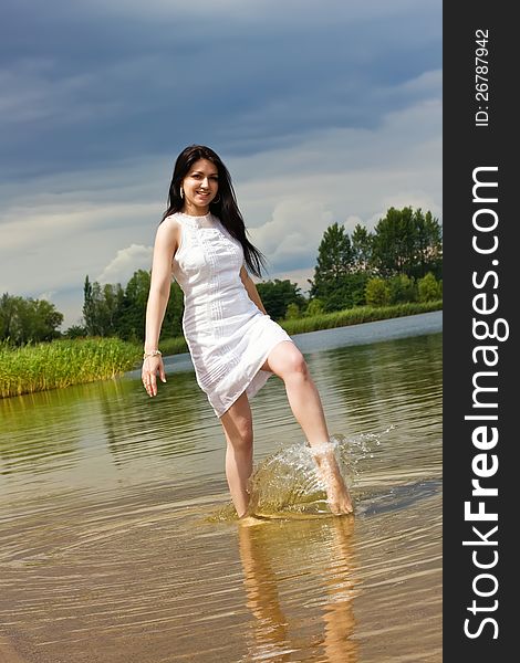 Young woman makes fun on the lake doing splashes of water