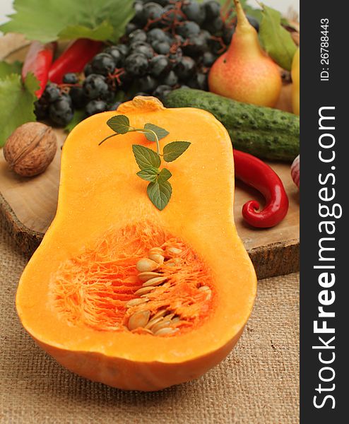 Half fresh pumpkin with other autumn fruits and vegetables