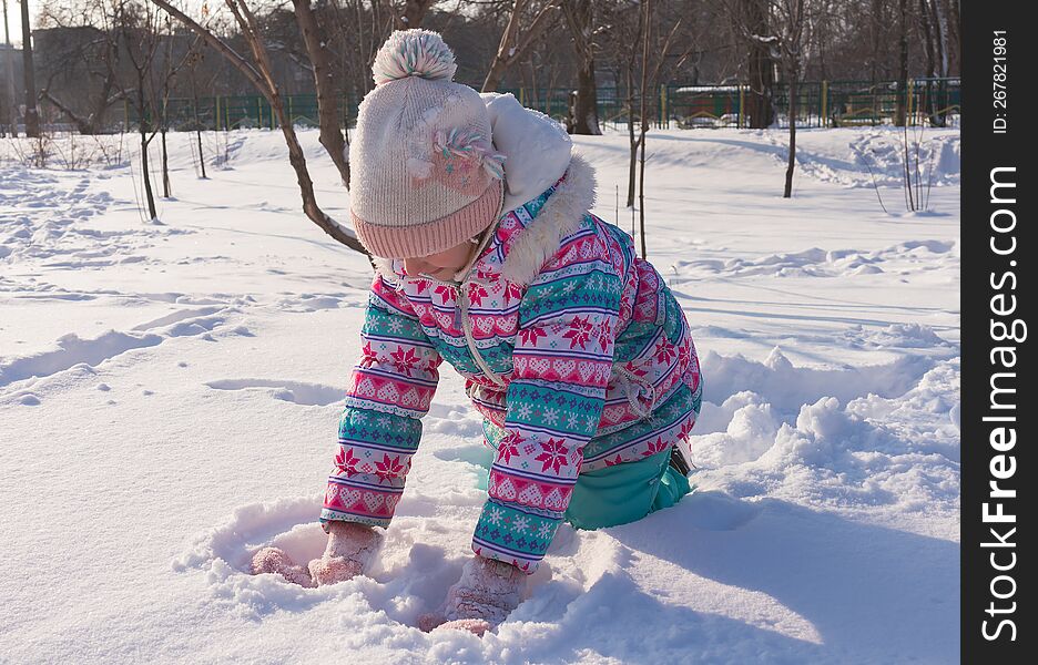 winter portrait of a girl 7-8 years old playing snowballs