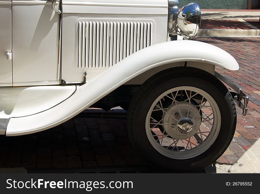 Side view of old antique automobile, showing hood vents, fender and headlights on brick road. Side view of old antique automobile, showing hood vents, fender and headlights on brick road