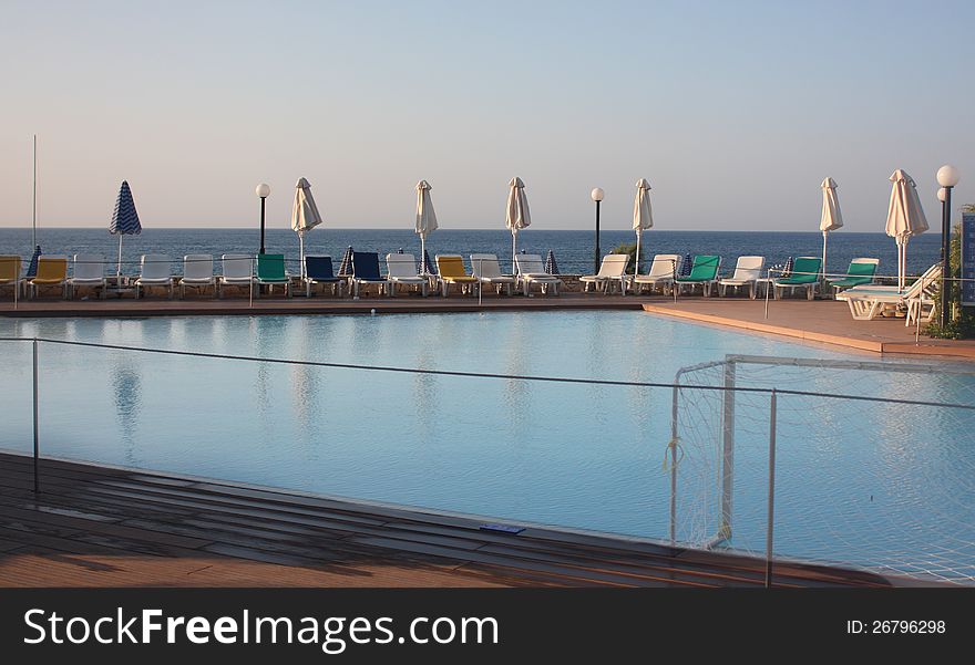 Pool on the seashore in luxury hotel with beach umbrellas and chaise lounges. Pool on the seashore in luxury hotel with beach umbrellas and chaise lounges