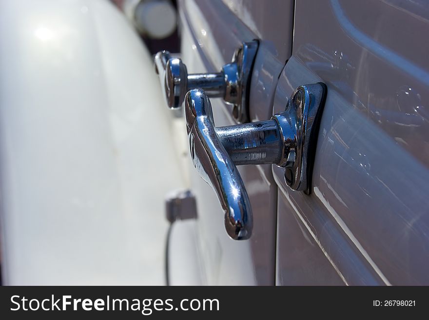 Close up of old chrome door handles on the side of an antique white automobile. Close up of old chrome door handles on the side of an antique white automobile.