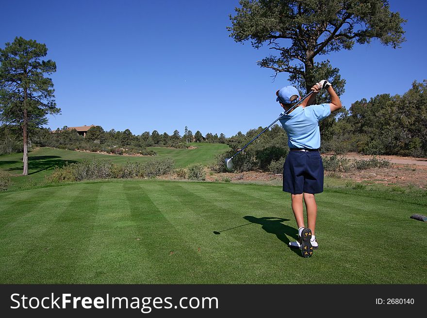 Young golfer hitting off tee