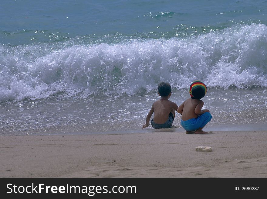 Two children on the seashore innocently watching the approaching waves. Two children on the seashore innocently watching the approaching waves